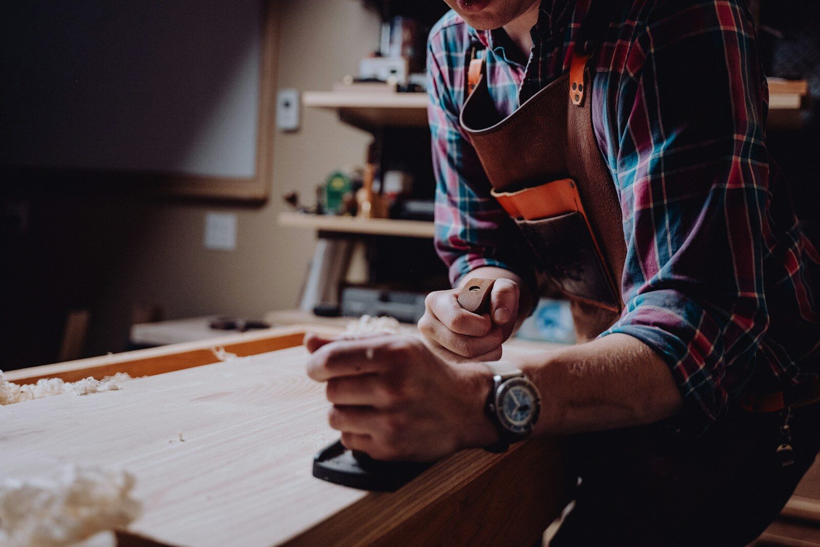 An adult student shaping a piece of wood at a workbench in an evening class