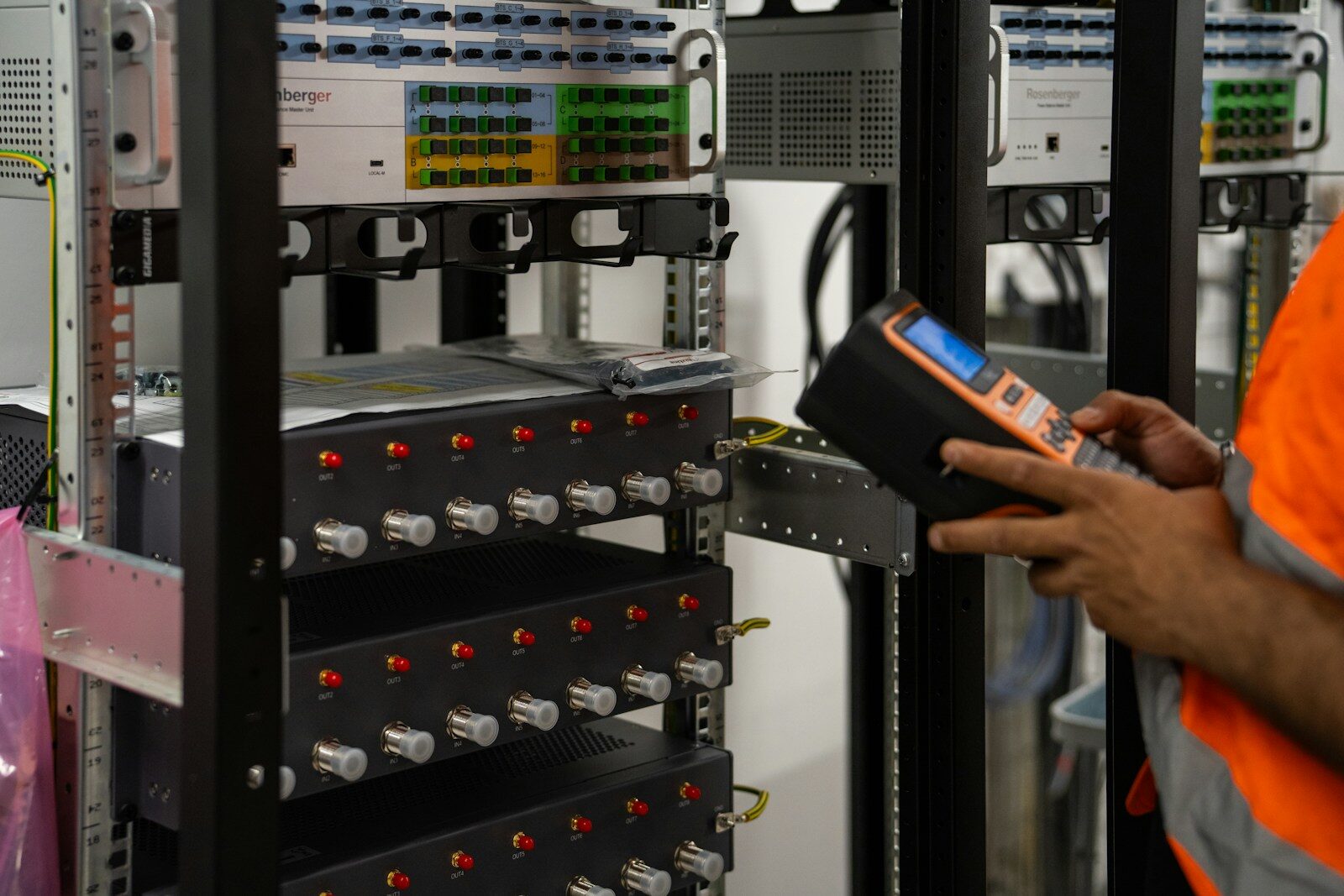 A technician inspecting server racks with a handheld diagnostic tool