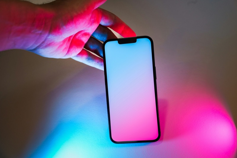 A person holding a smartphone, its screen lit in a darkened room