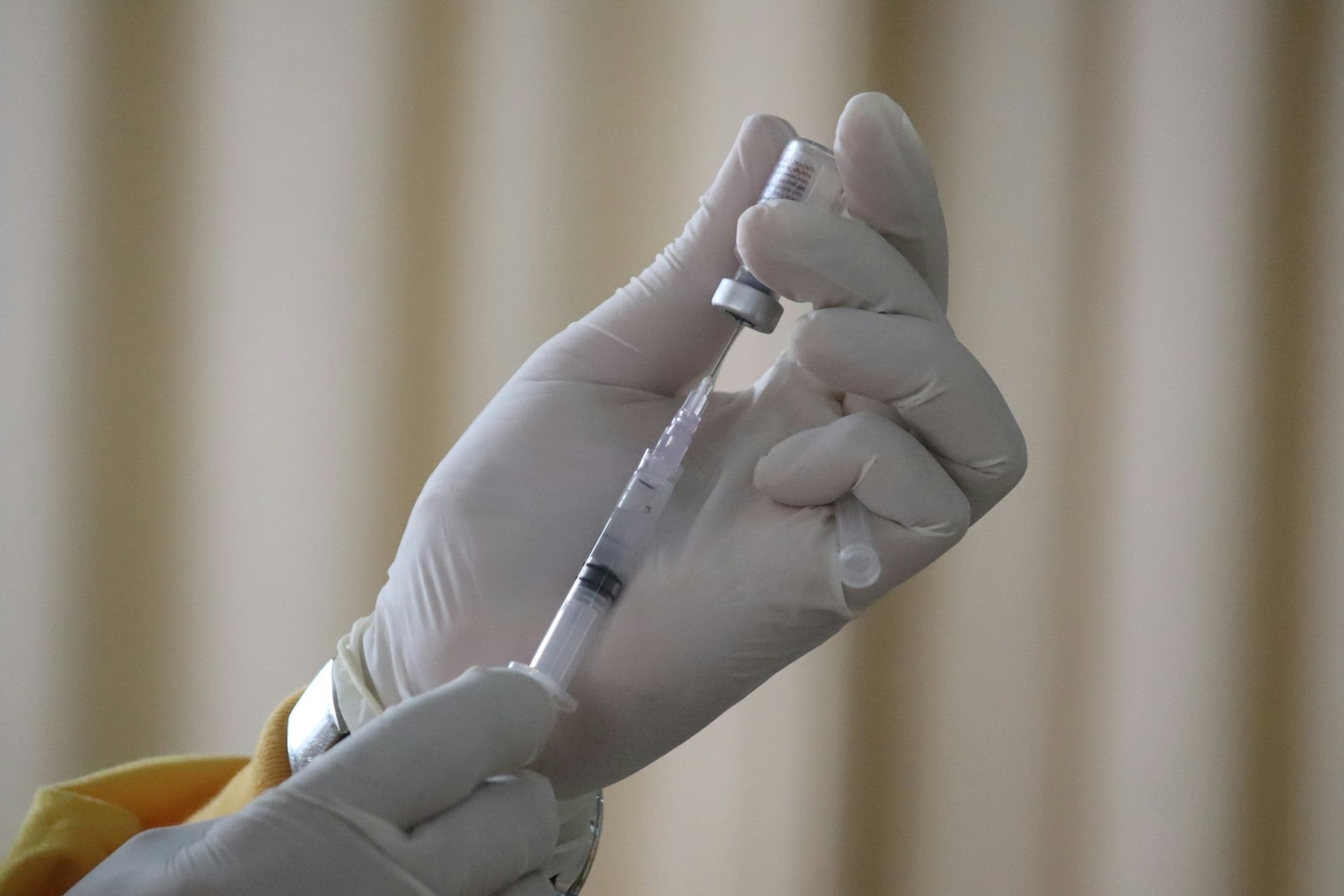 A vaccine vial and syringe on a clinical surface.