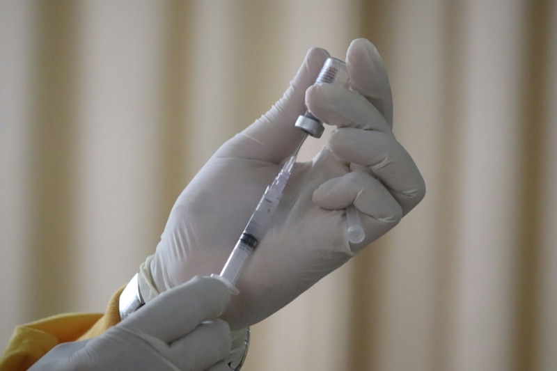A vaccine vial and syringe on a clinical surface.