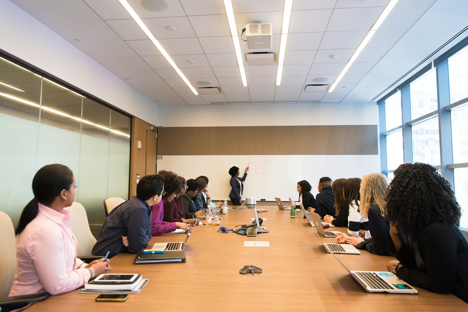 Directors seated around a boardroom table listening to a woman speaking