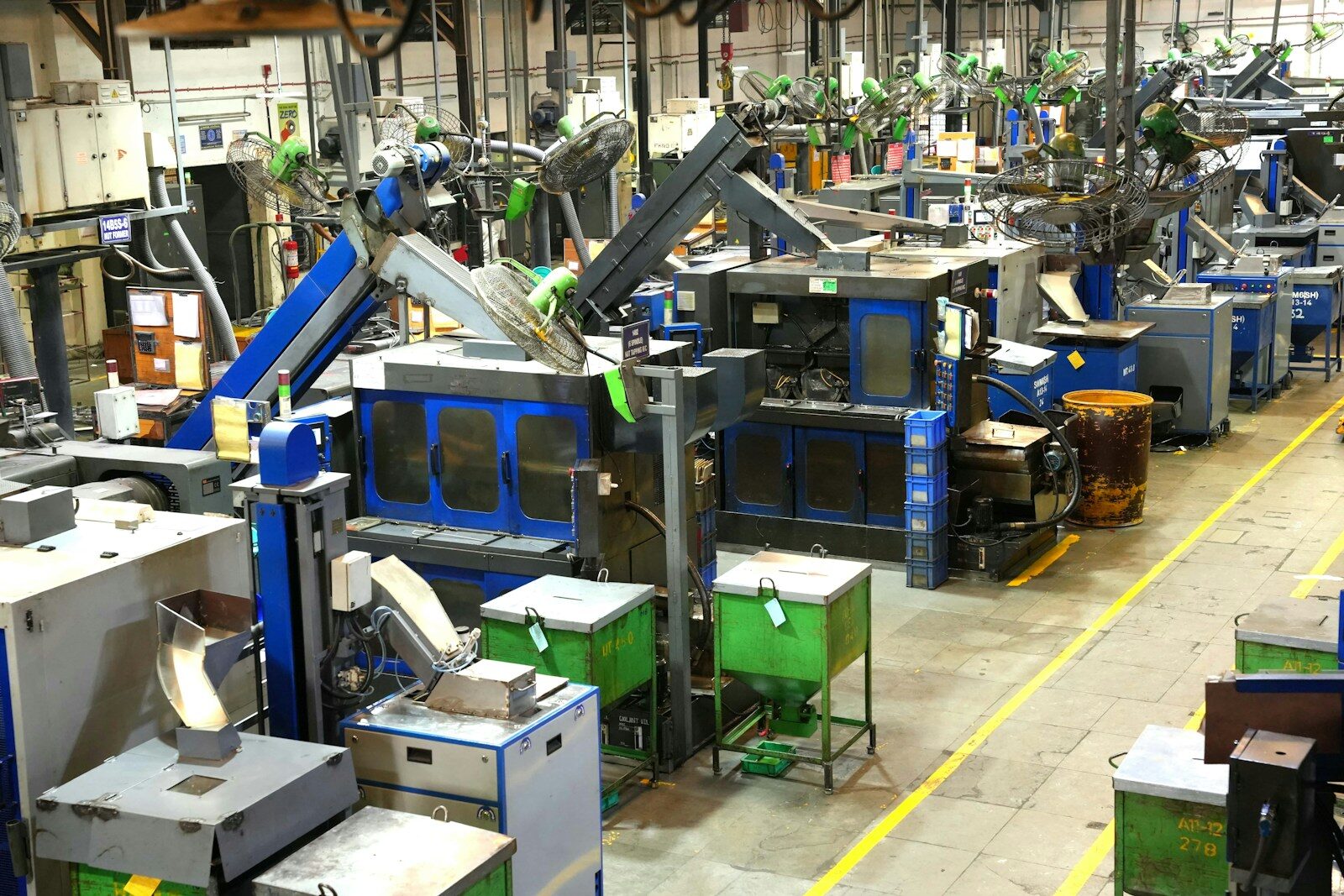 A factory floor lined with machine tools and extraction ducting, a yellow walkway marked down the aisle.