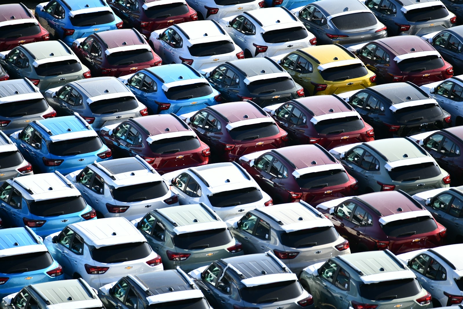 Rows of new cars parked in a distribution lot.