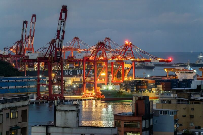 Gantry cranes and container vessels at a commercial terminal at dusk.