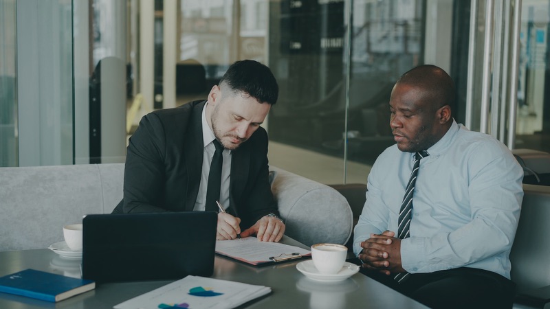 Two people reviewing and signing a contract.