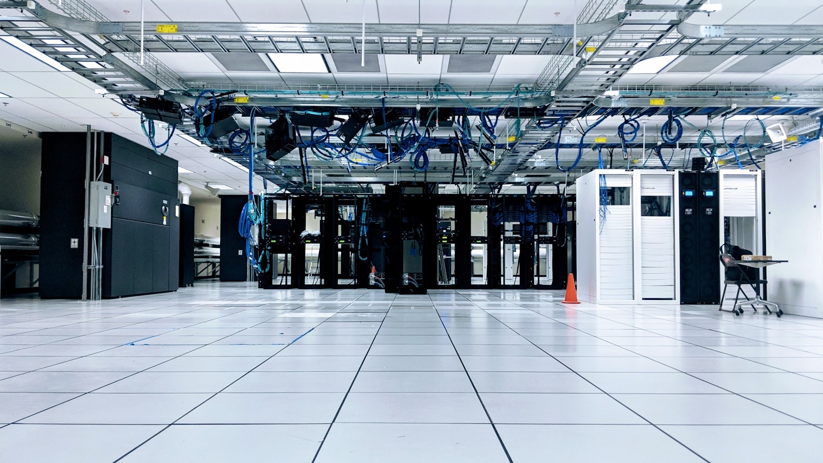 A server room with rows of black and white cabinets under blue cables