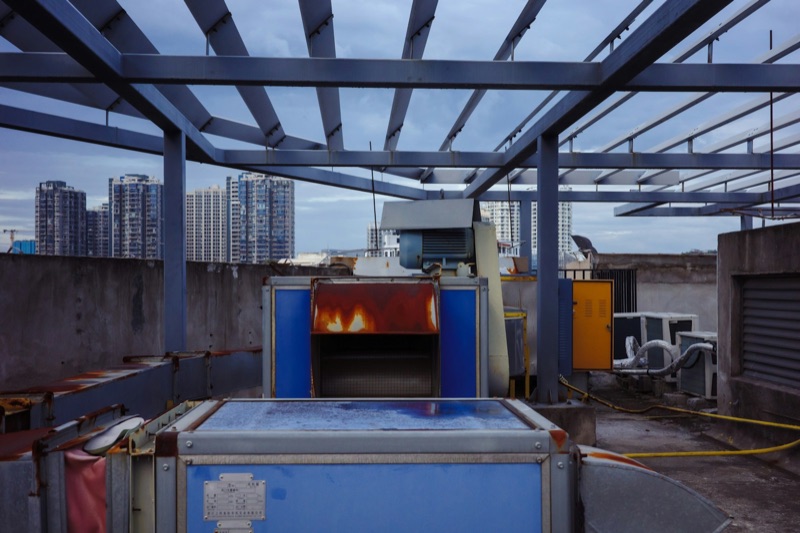 Ageing ventilation and cooling plant on a rooftop, with newer towers behind.