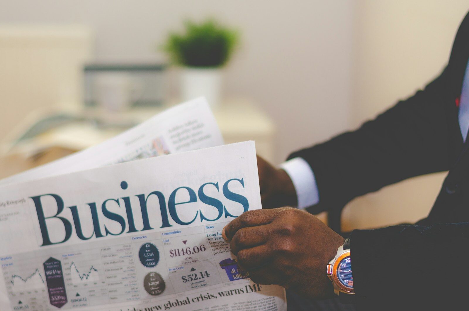 A person in a suit reading the business pages of a newspaper