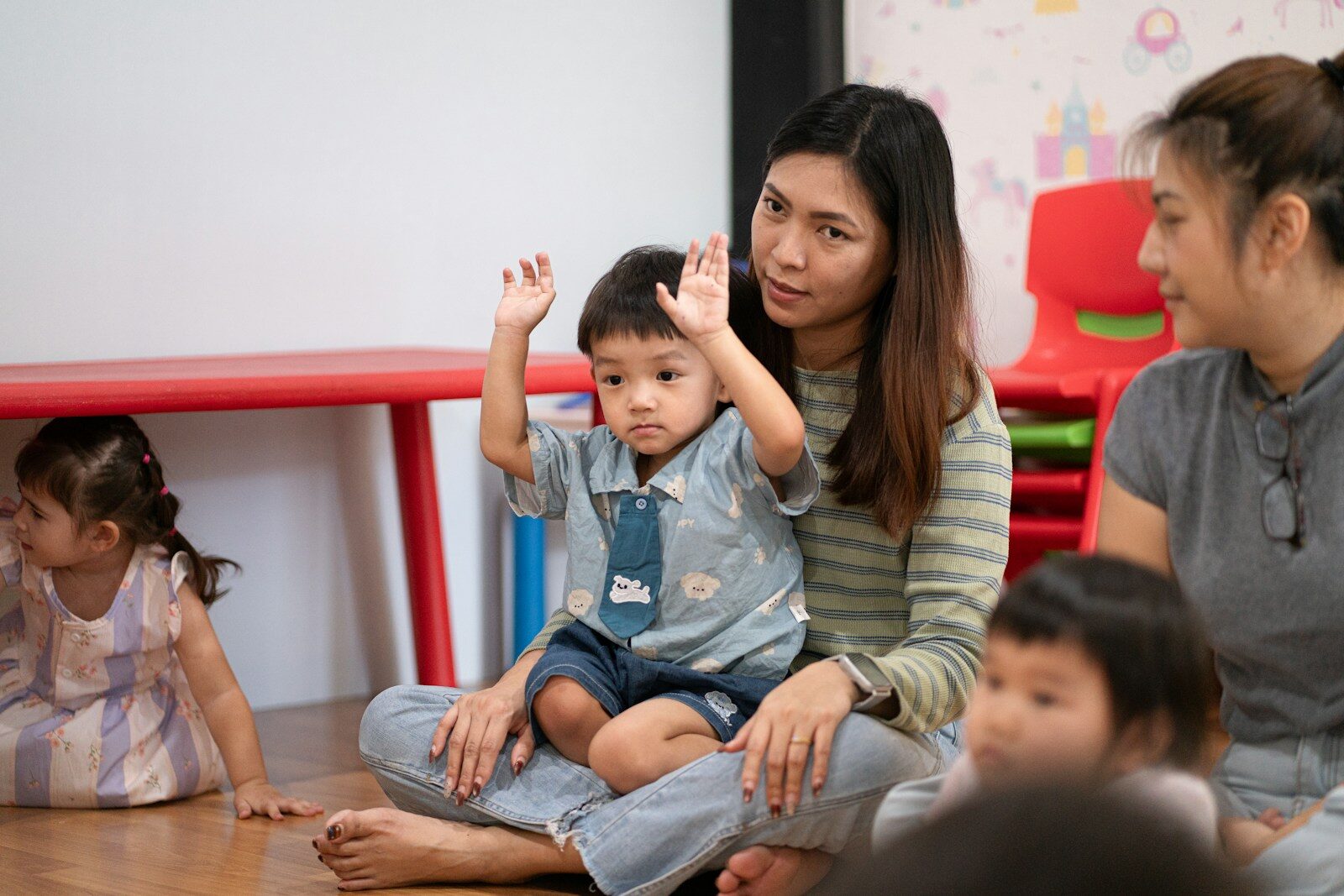 A carer with a small child in a nursery room.
