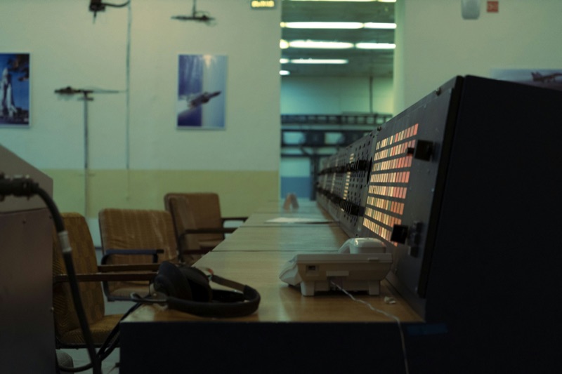 A control room lined with monitors and empty operator chairs.