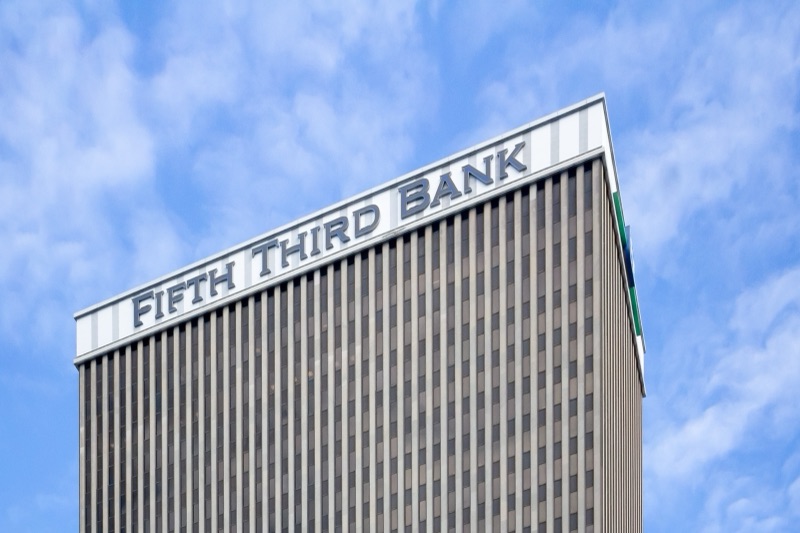 The top of the Fifth Third Center tower in Cincinnati, with the words Fifth Third Bank across its crown against a blue sky with clouds.