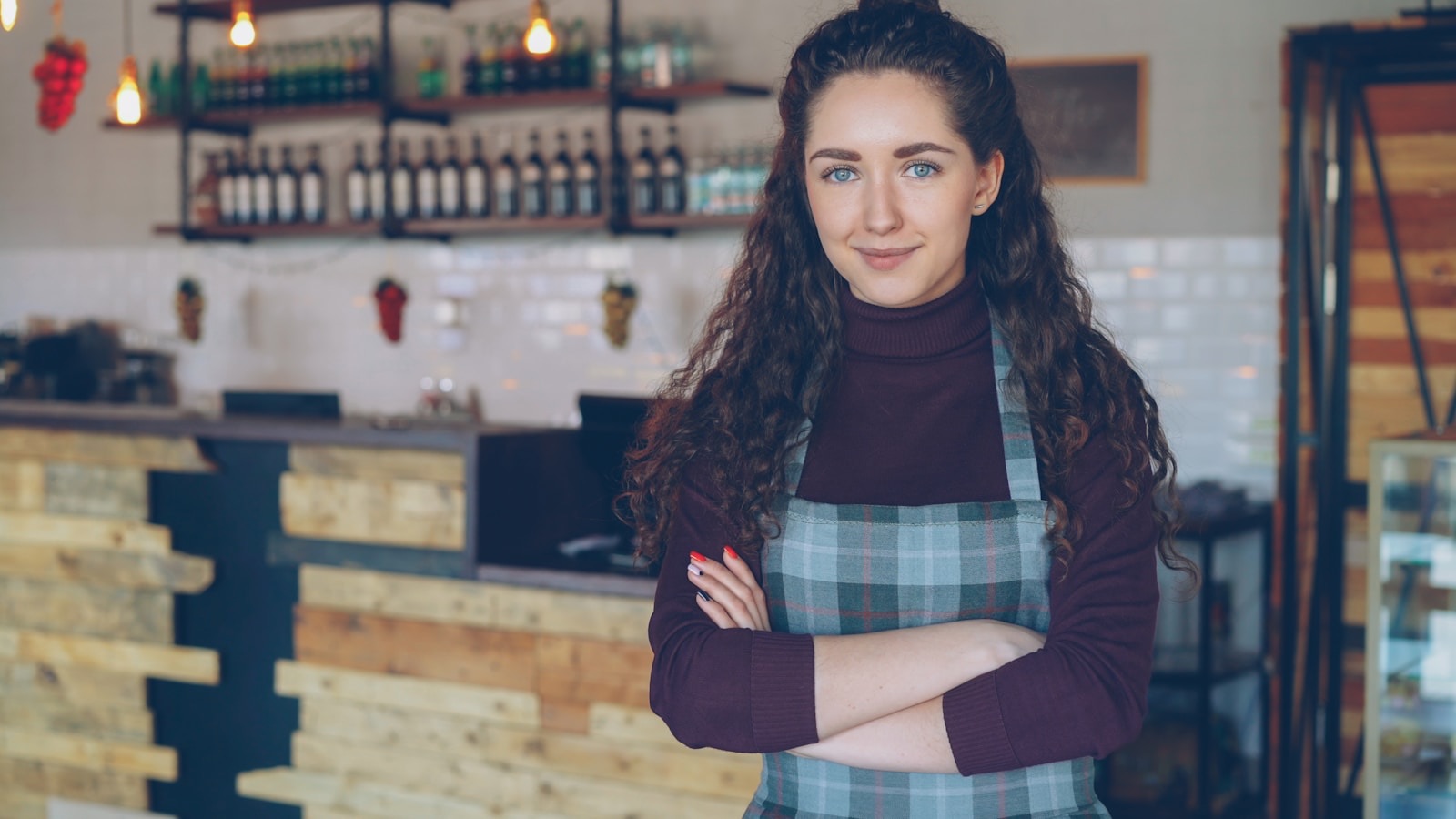 A smiling owner standing behind the counter of her coffee shop