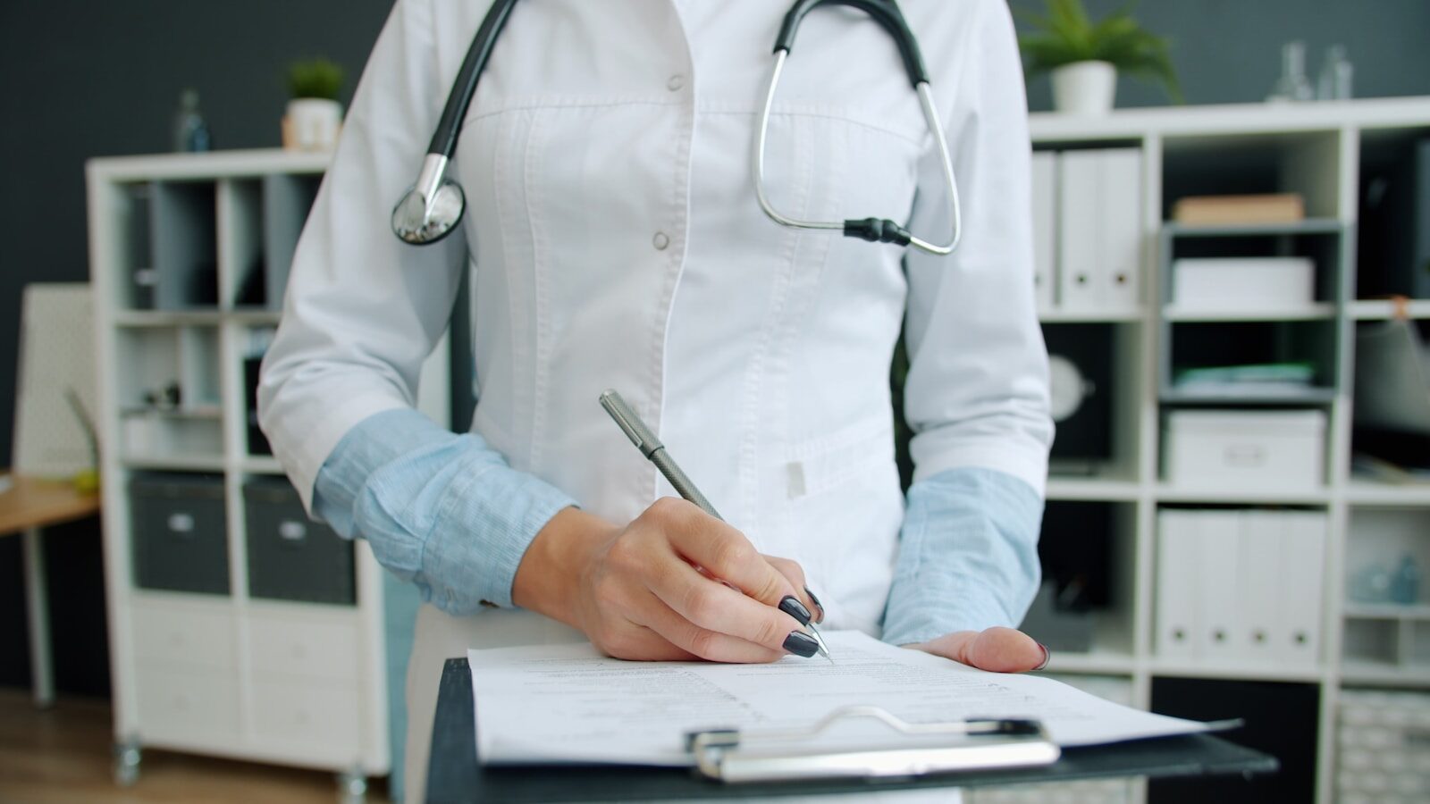 A doctor's hand completing a patient's medical records