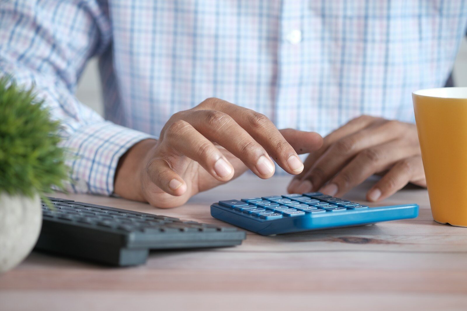 A person working through household figures on a calculator at a desk