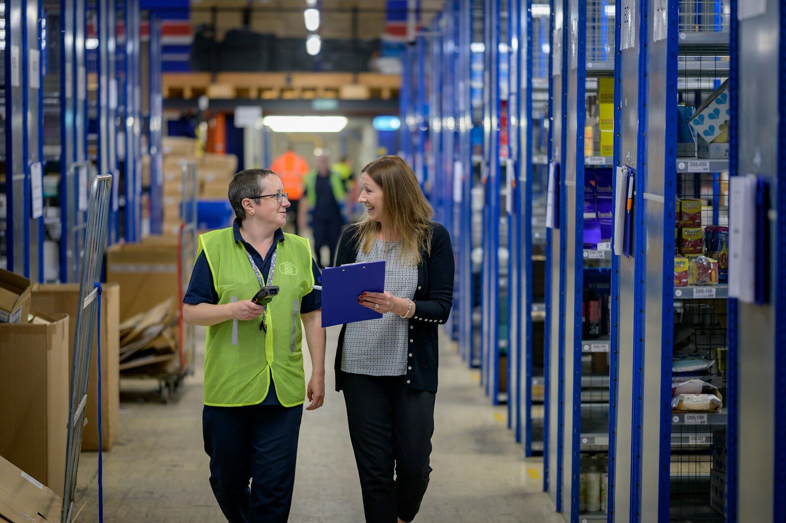 A man and a woman working among the racking on a warehouse floor