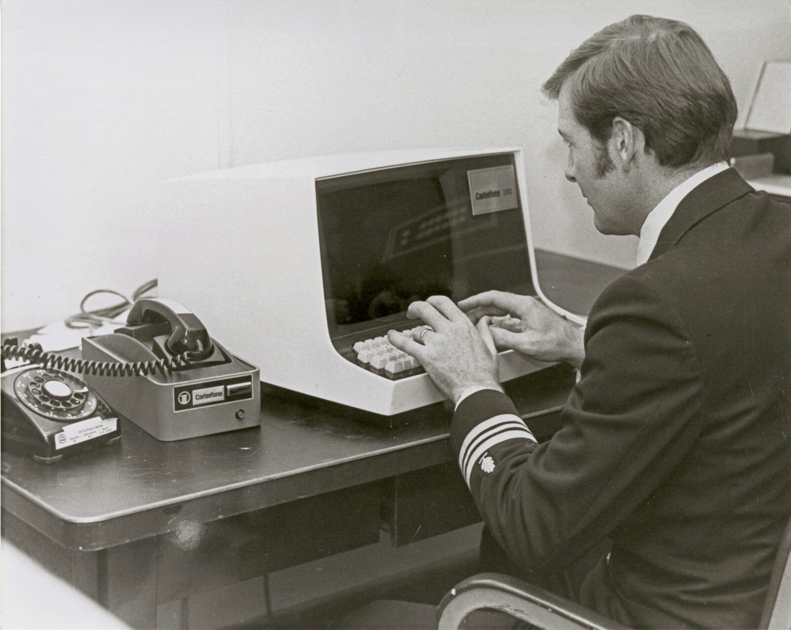 A man in uniform typing at a vintage computer terminal