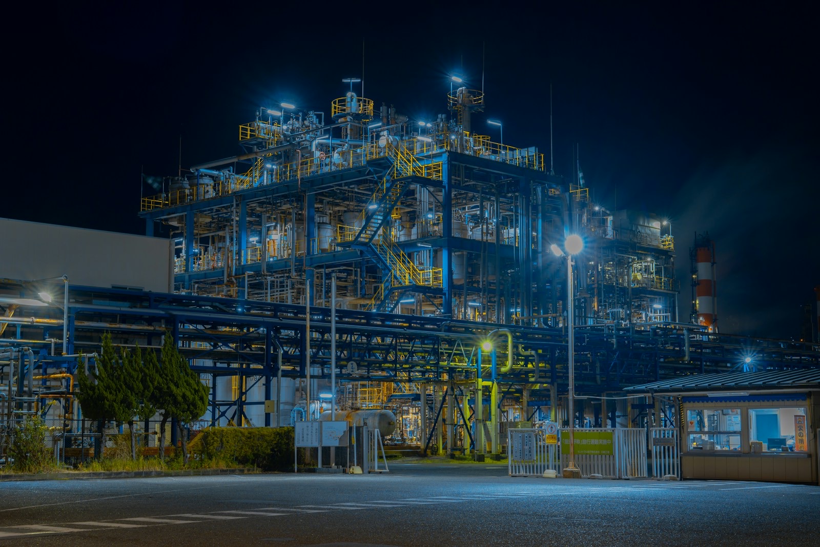 A gas processing plant lit at night, its pipework and flare stack picked out against a dark sky.