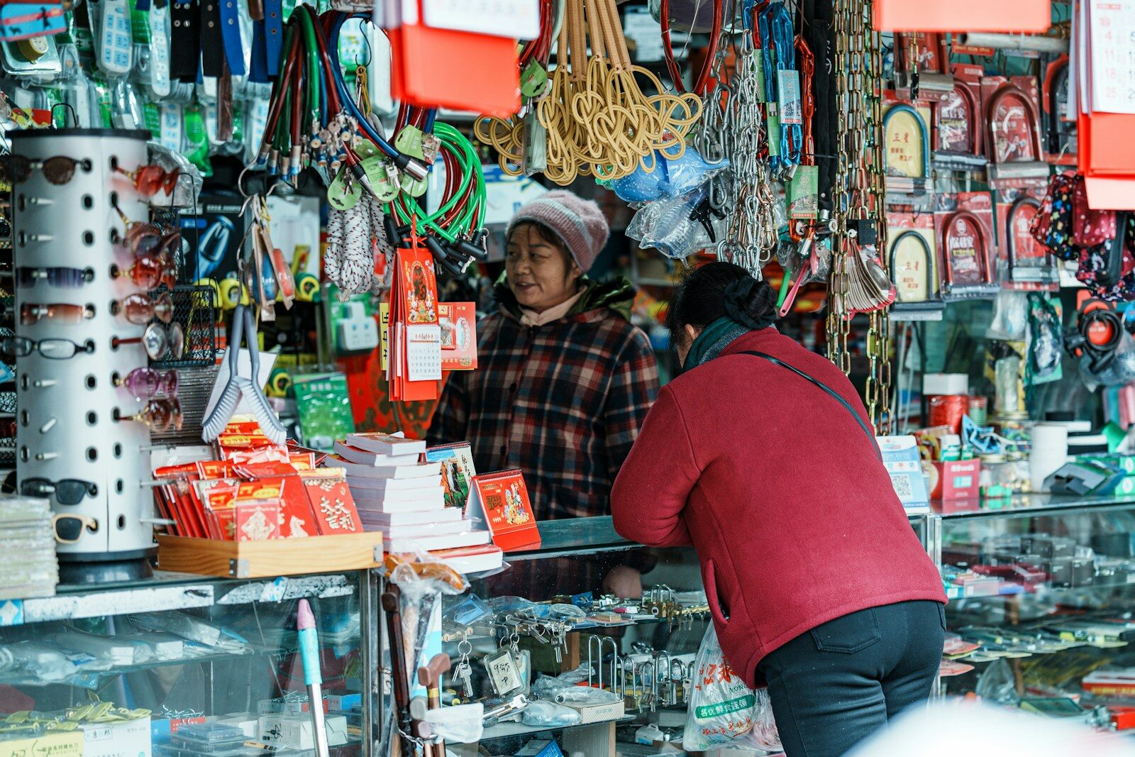 Two women running a busy market stall, selling goods to passing customers