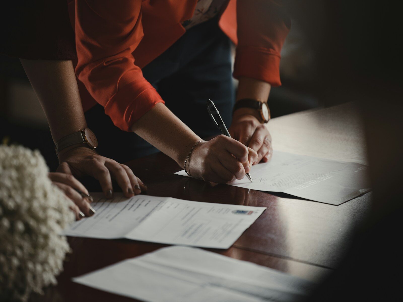 A person in an orange shirt marking up a printed contract