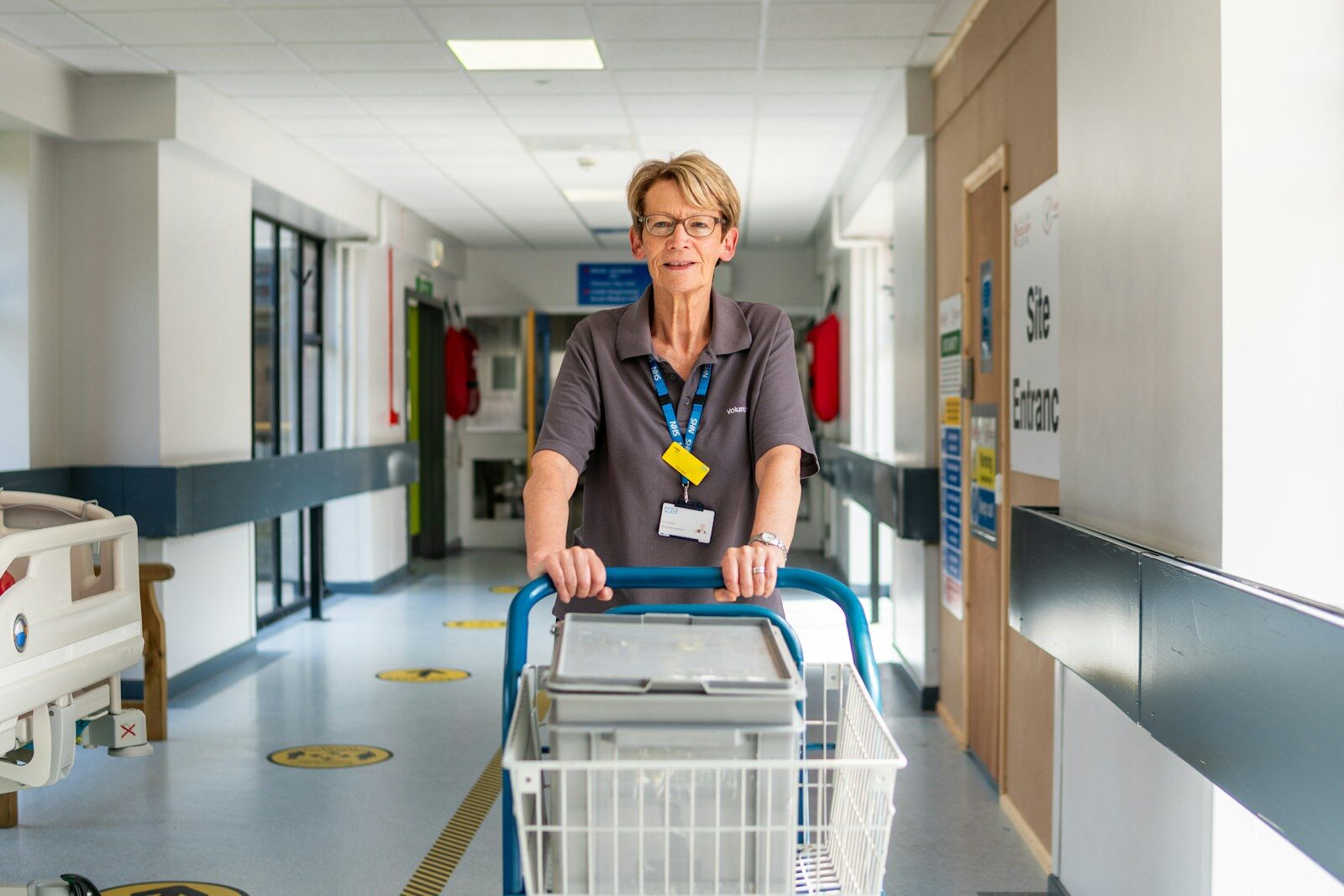 Volunteer pushes trolley in hospital corridor