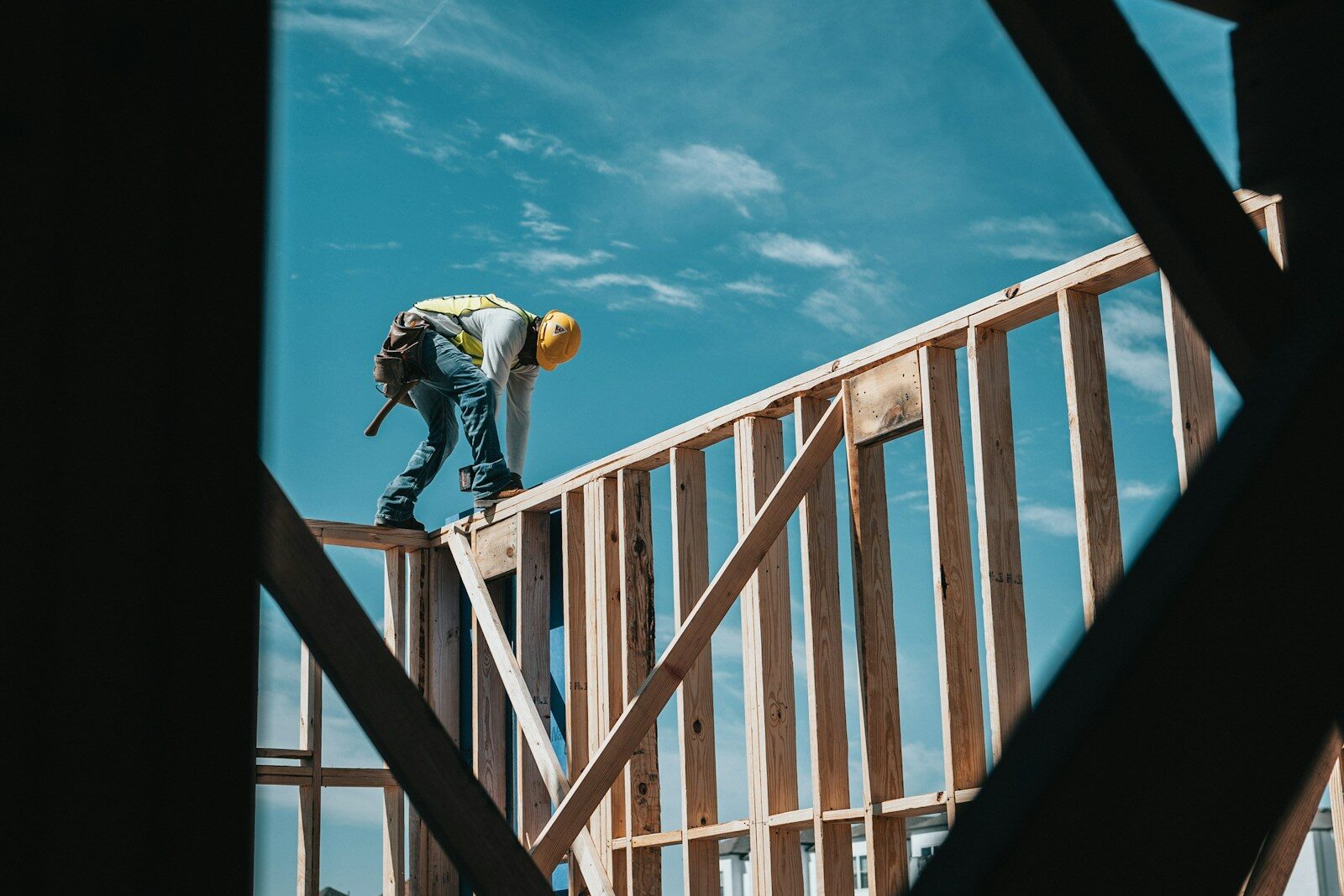 A construction worker in a hard hat standing on an exposed building frame