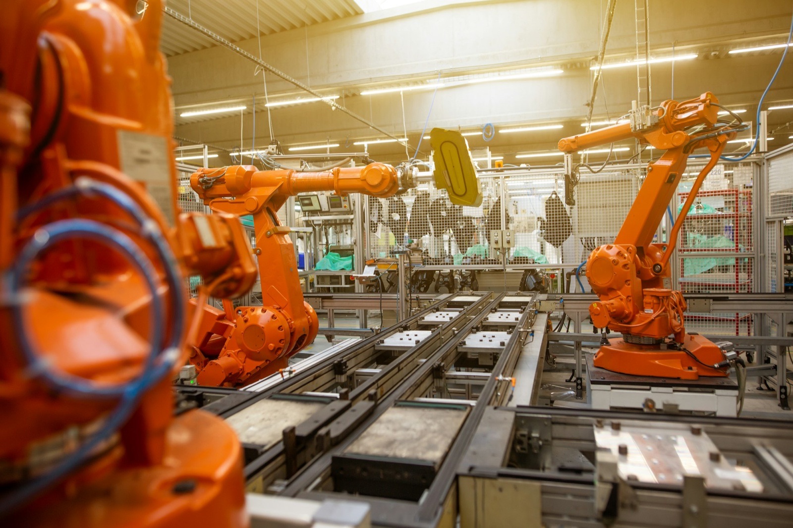 Orange industrial robot arms arranged along an automated factory assembly line