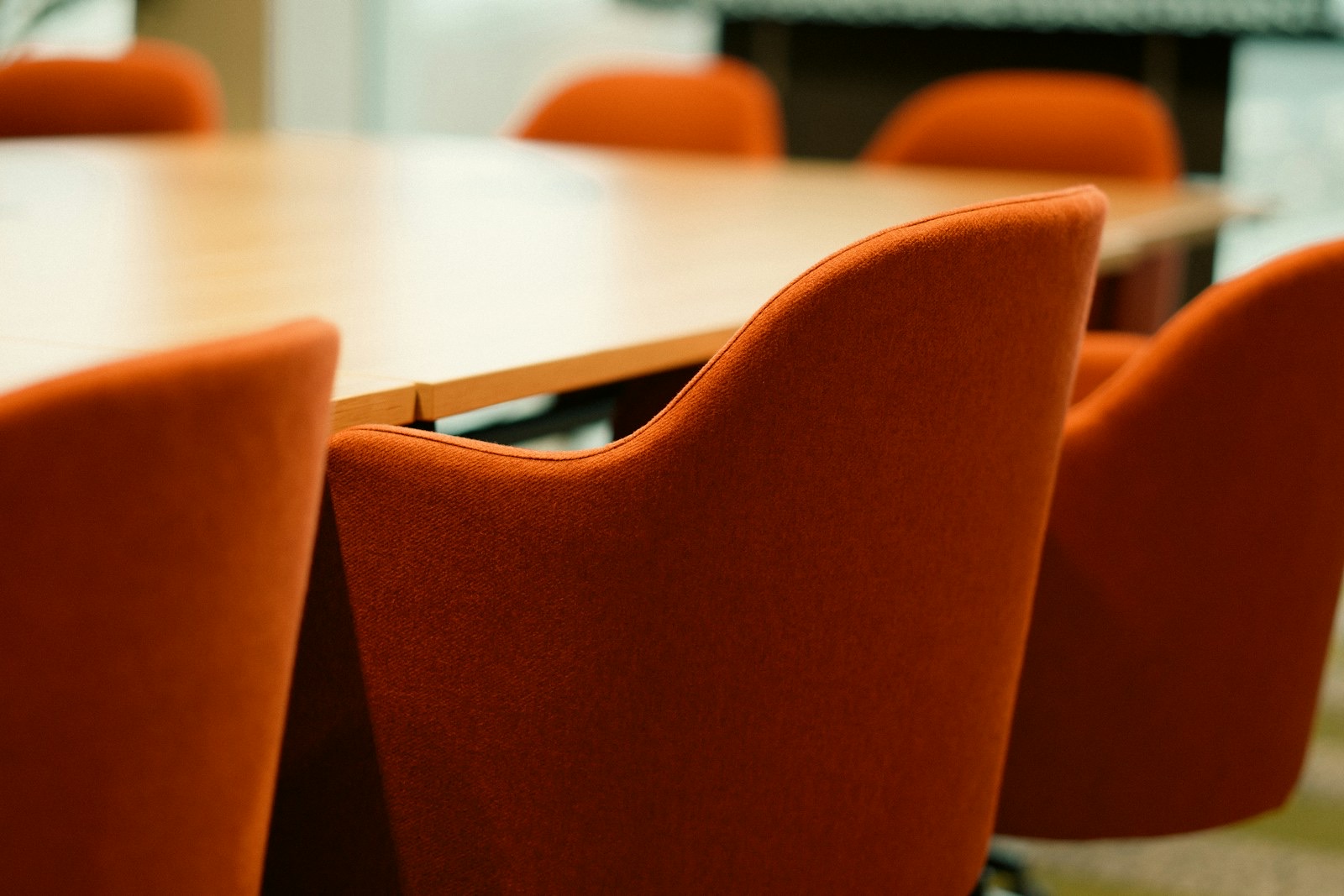 Conference meeting table seating interior. Professional office space showcasing upholstered chairs aligned around wooden table creating structured environment suitable corporate presentations strategy sessions business training leadership meetings.