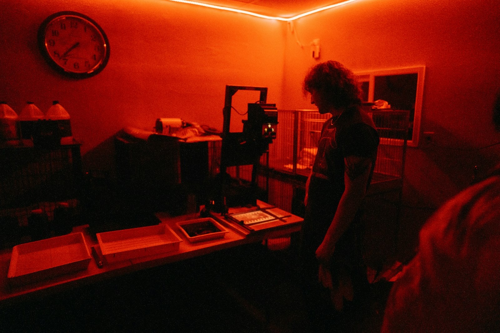 A photographer making a print from 35mm film in a darkroom.