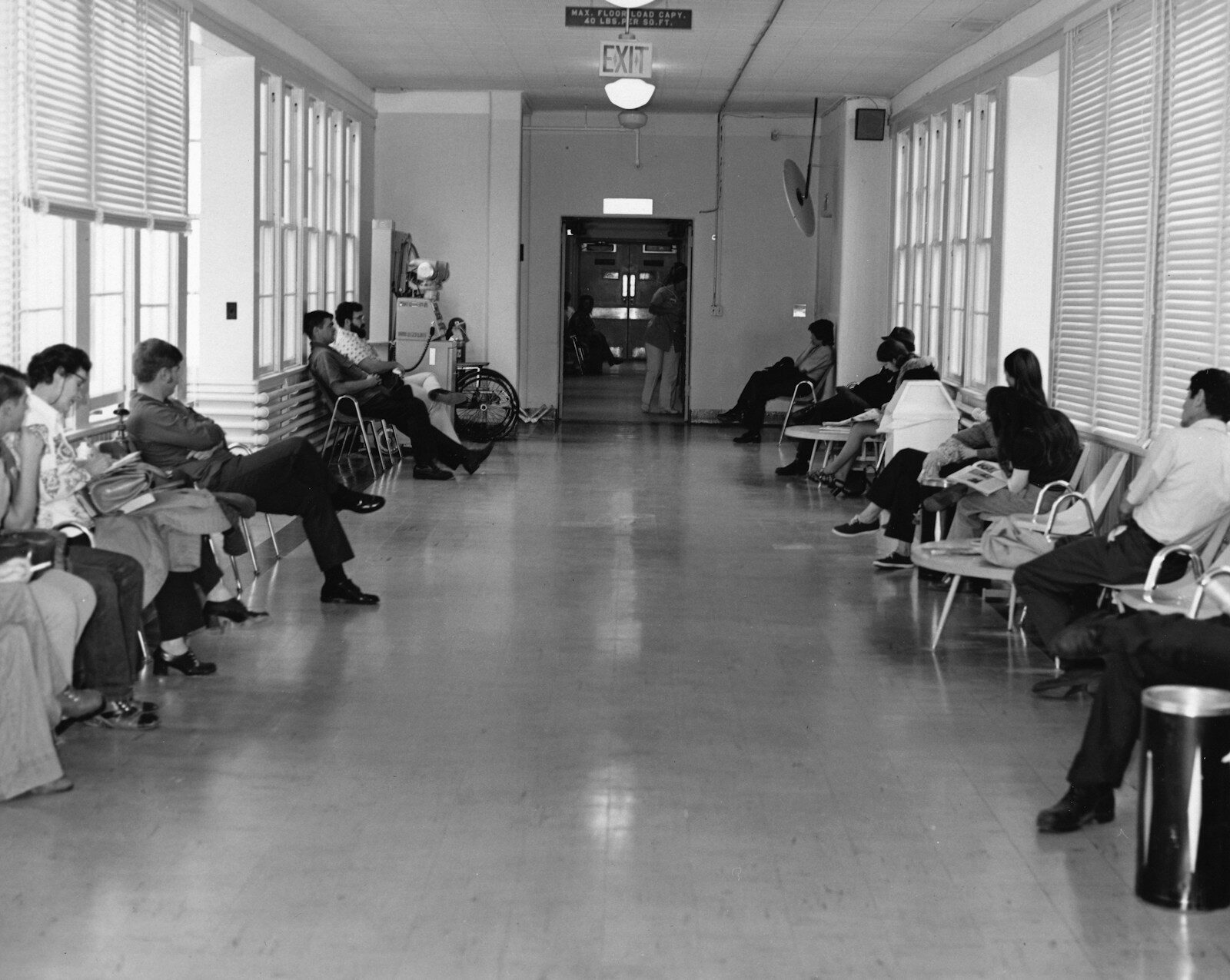 Patients waiting in a corridor lined with chairs