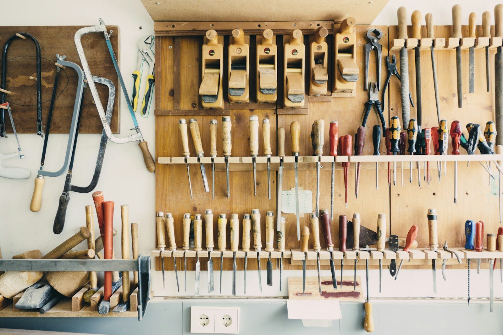 An assortment of hand tools racked and organised in a home workshop