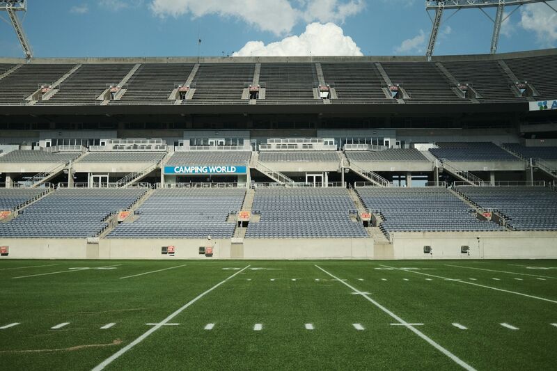 An empty American football field with vacant bleachers under an open sky