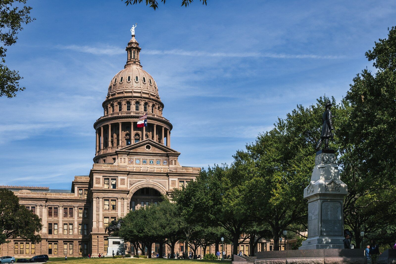 A state capitol building with a domed tower and flag