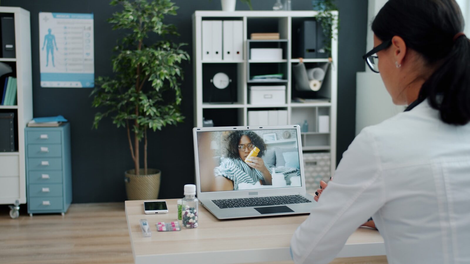 A clinician consulting a patient by video call on a laptop