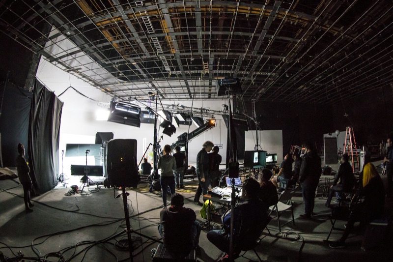 A film crew working around a camera on set.