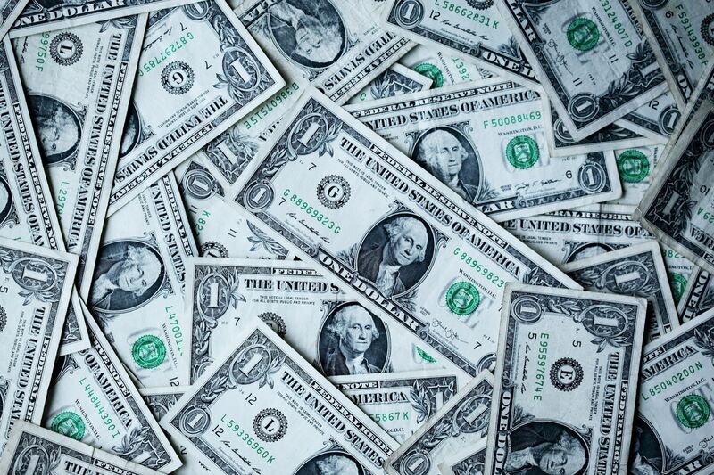 A scattered layer of US one-dollar bills photographed from above.