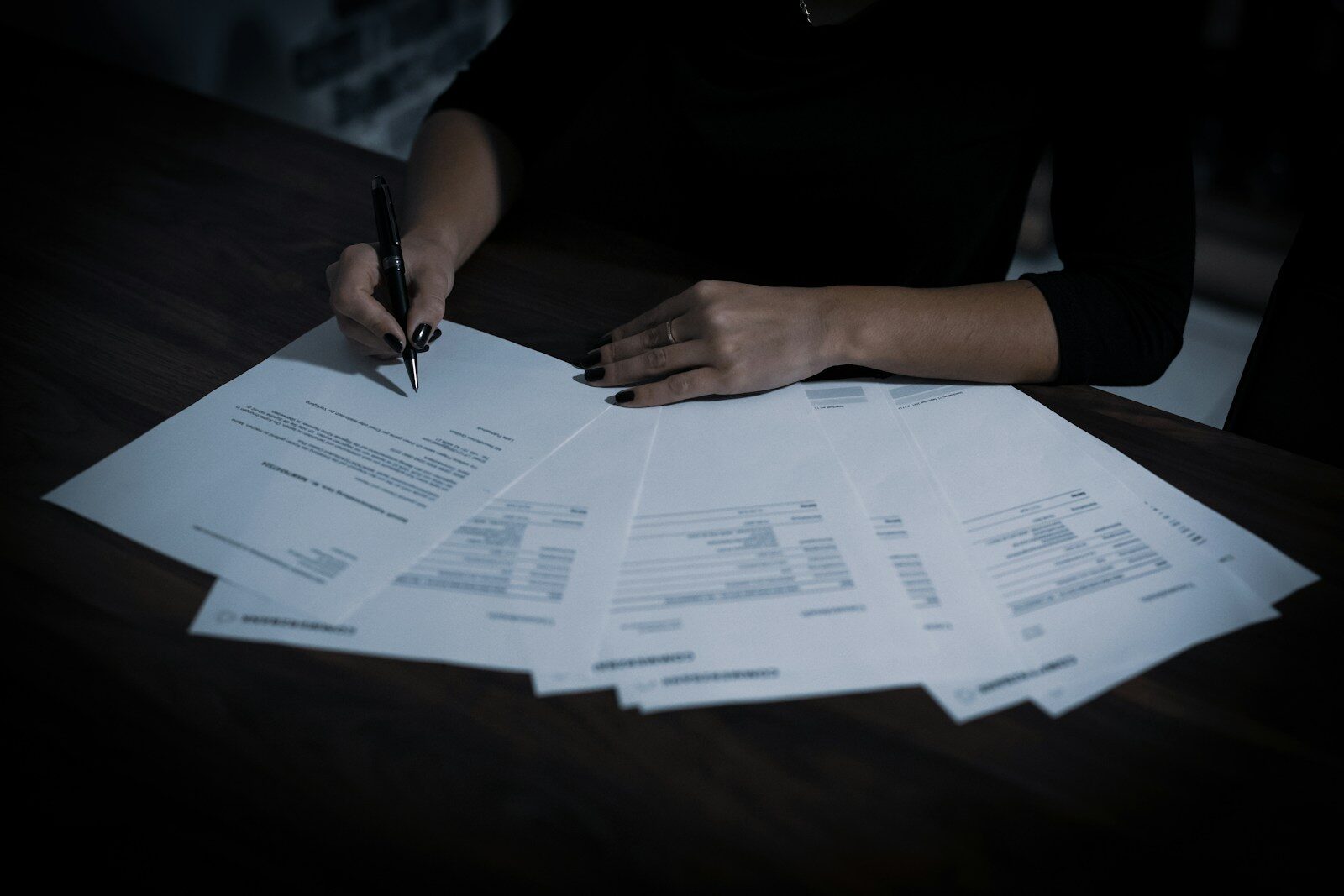 A person signing a contract with a ballpoint pen.