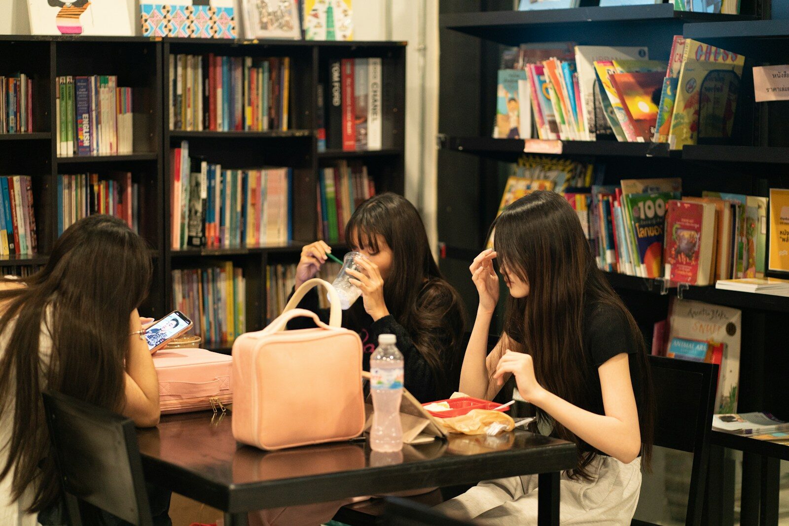 Three young women sitting together at a table in a library cafe