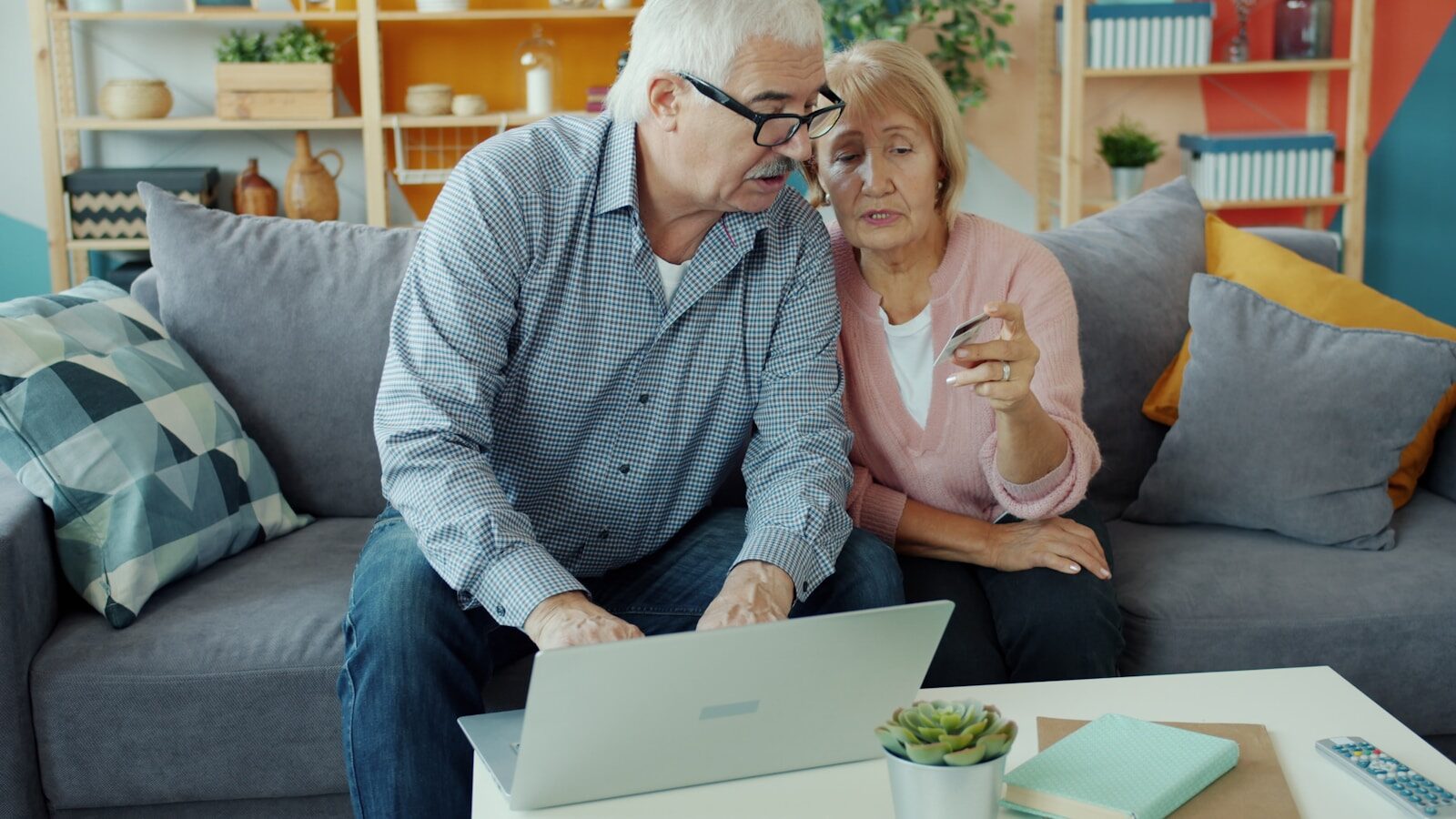 An older couple reviewing their accounts together on a laptop at home