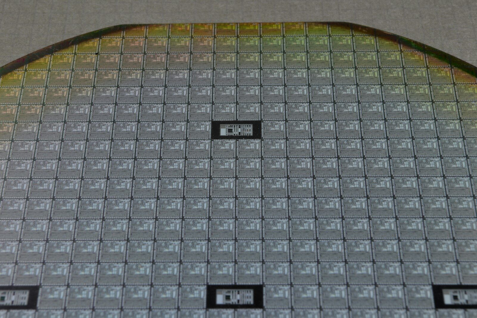 Close-up of a silicon wafer patterned with a grid of rectangular chip dies.