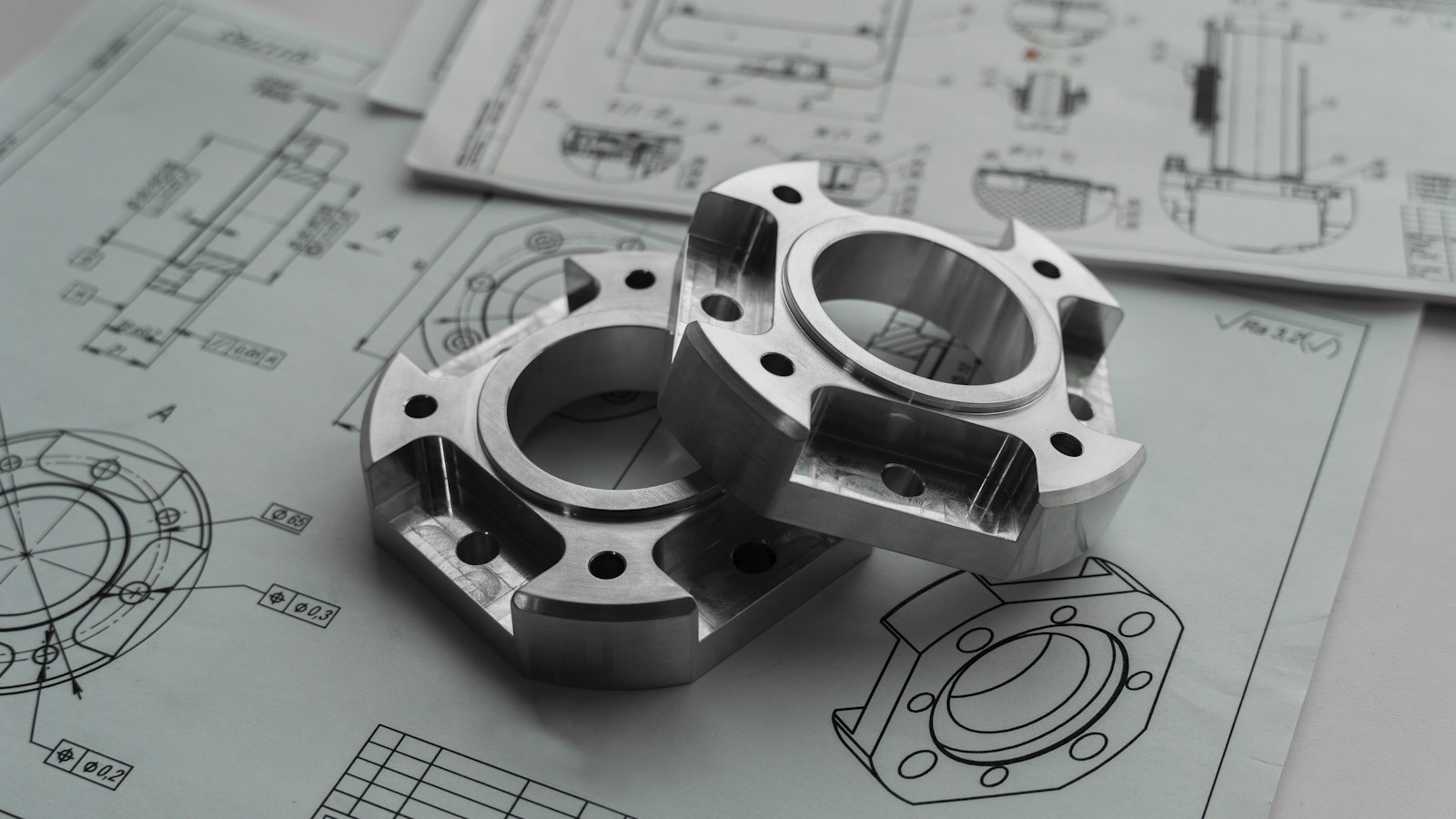 Two machined metal flanges resting on engineering drawings.