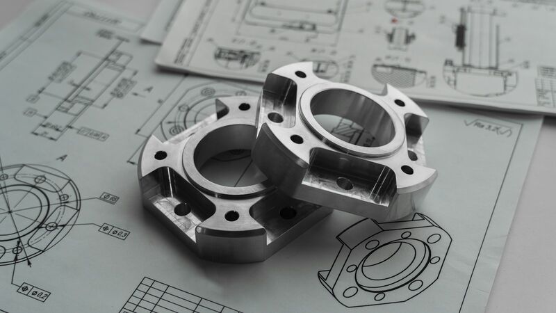 Two machined metal flanges resting on engineering drawings.