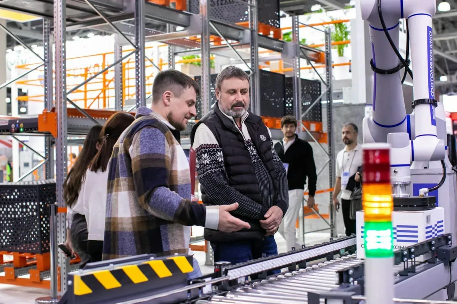 Attendees observe a robotic automation system at TRST Expo. Demonstration of advanced robotics for logistics and warehouse automation. A modern industrial exhibition featuring smart technology and innovation.